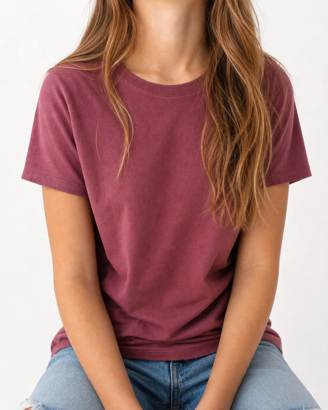 Girl seated, shown from the collarbone down, wearing a plain muted-berry t-shirt